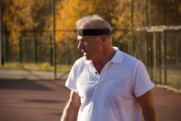 Starszy mężczyzna po sześćdziesiątce gra w tenisa. - Zdjęcie, obraz
