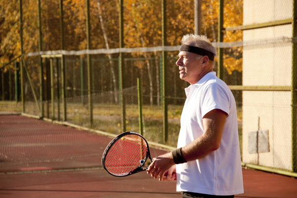 Un anciano mayor de sesenta años juega al tenis
. - Foto, Imagen