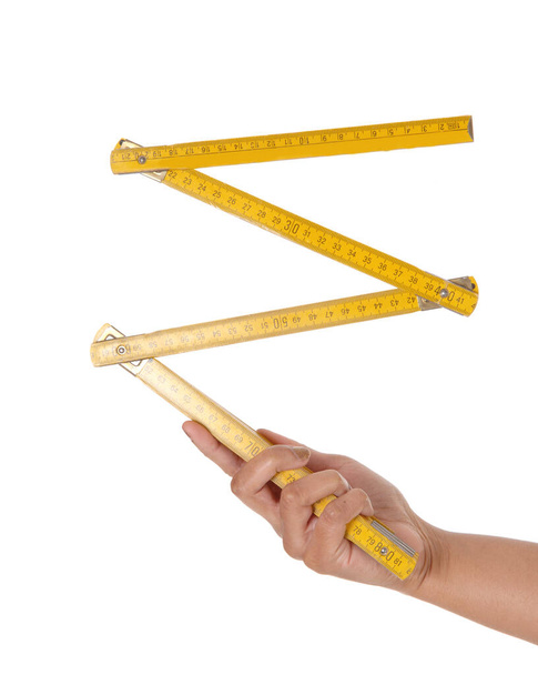 A close up image of a hand holding a European yellow wood ruler a .zollstock, a carpenter tool, isolated for white background. - Foto, Bild