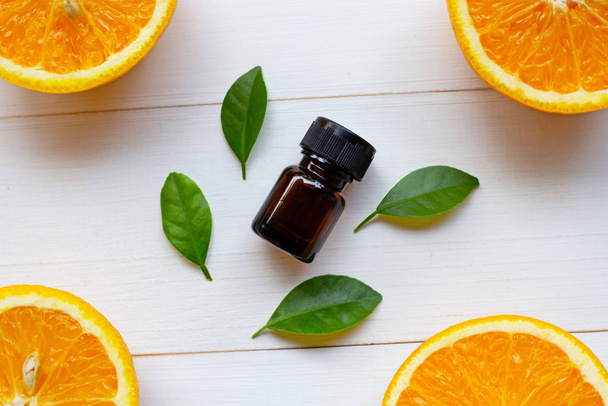 Orange essential oil with fresh fruits on white wooden background. - Foto, afbeelding