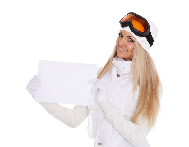 Young  woman in ski glasses and  winter warm clothes with empty board for the text on a white background. Winter sports. - Фото, зображення