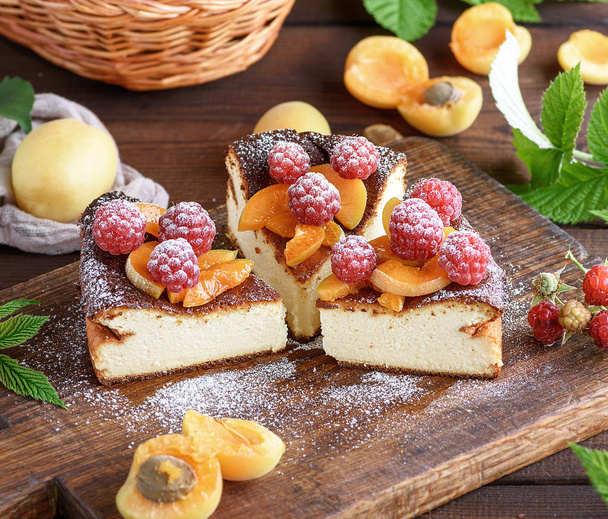 pie with raspberries and apricots on a brown wooden board, close up - Photo, Image