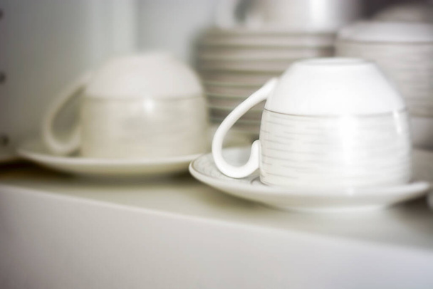 decorated coffee cups kept in a shelf of a white pantry. Interior shot - Photo, Image