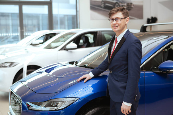 Mature businessman at car dealership - Fotó, kép