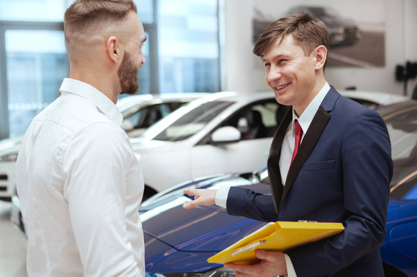 Handsome man buying new car at the dealership - Foto, Imagen
