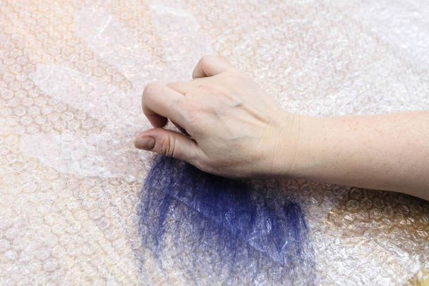 workshop of hand making a fleece gloves from blue Merino sheep wool using wet felting process - craftsman spreads first layer of fibers on cutting pattern - Fotoğraf, Görsel