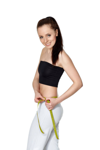 The beautiful young woman measures a volume of waist on a white background.  Concept of healthy lifestyle. - Foto, afbeelding