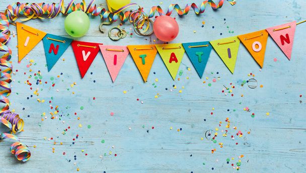 Invitation concept with party streamer and colorful rainbow colored bunting border and copy space over blue wood with scattered confetti - Φωτογραφία, εικόνα
