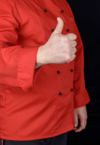 cook in red shows gesture like, black background - Fotoğraf, Görsel