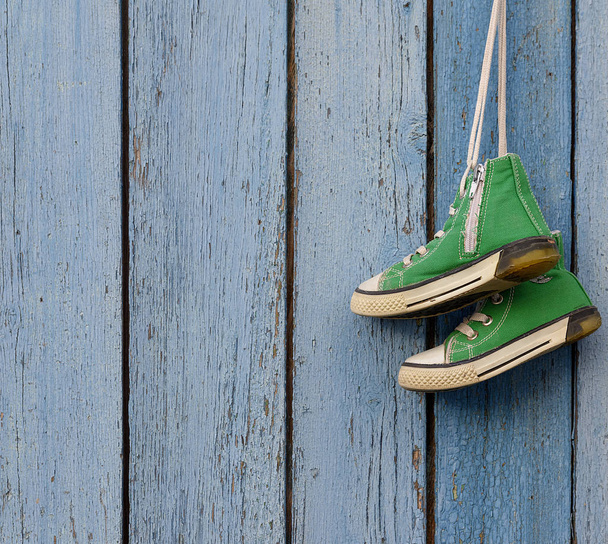 pair of used green textile shoes hang on a blue background, copy space - Foto, afbeelding