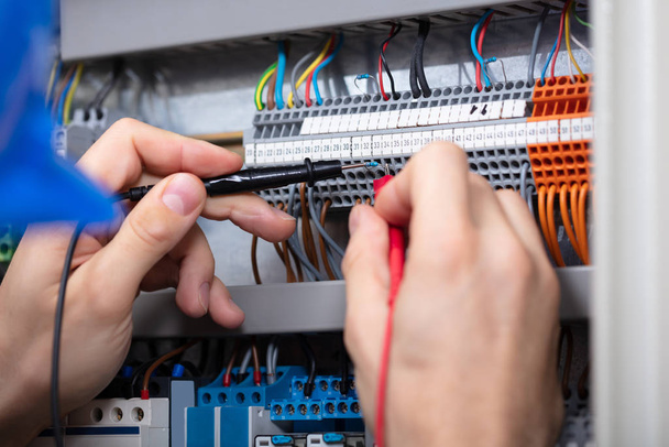 Close-up Of A Male Electrician Examining Fuse Box With Multimeter - Photo, image