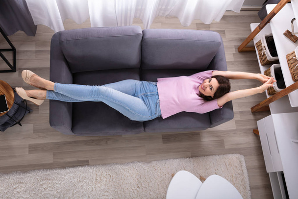 Smiling Young Woman Lying On Sofa At Home - Foto, afbeelding