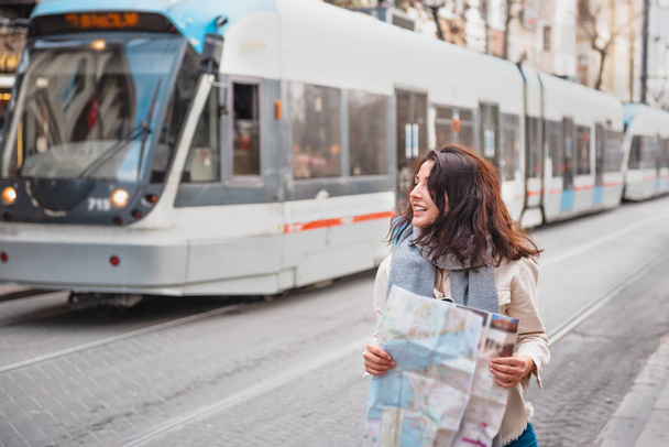 Cute girl explores streets of city with map - Foto, Imagen