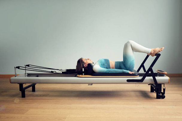 leotard workout pilates training. athletic pilates reformer exercises. pilates machine equipment. young asian woman pilates stretching sport in reformer bed instructor girl in a studio - Photo, Image