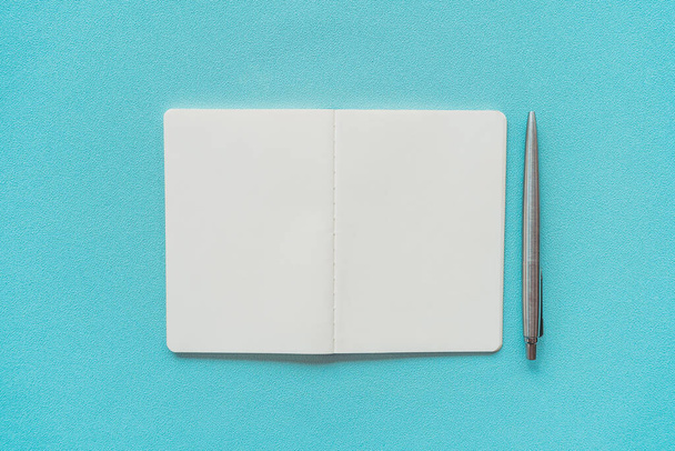 Cuaderno y pluma sobre fondo de textura azul
. - Foto, imagen