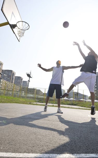 Streetball juego de baloncesto con dos jóvenes jugadores en la mañana temprano en la cancha de la ciudad
 - Foto, imagen
