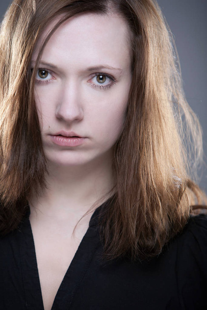 young acting student with intense look against gray background - Foto, afbeelding