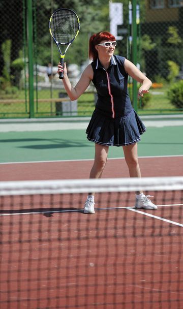 young fit woman play tennis outdoor on orange tennis field at early morning - 写真・画像