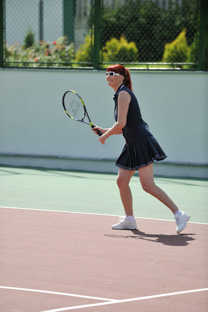 Jeune femme en forme jouer au tennis en plein air sur un terrain de tennis orange tôt le matin
 - Photo, image