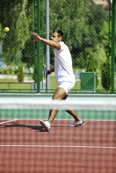 young man play tennis outdoor on orange tennis court at early morning - Foto, Imagem