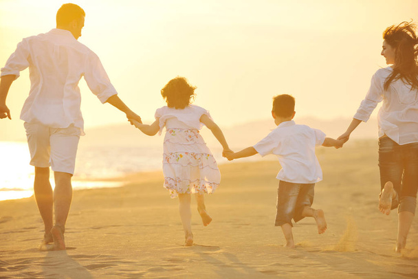 happy young family have fun on beach run and jump  at sunset - Foto, Bild