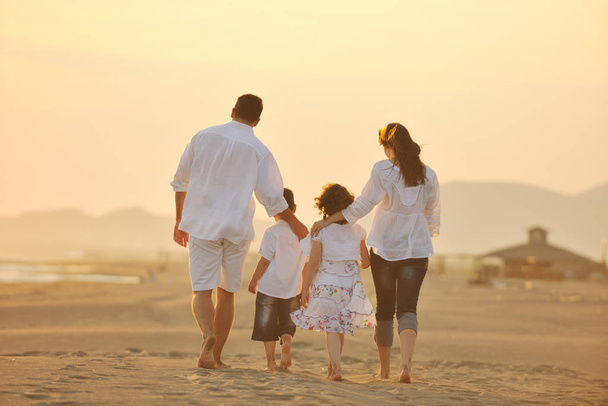 happy young family have fun on beach run and jump  at sunset - Foto, imagen