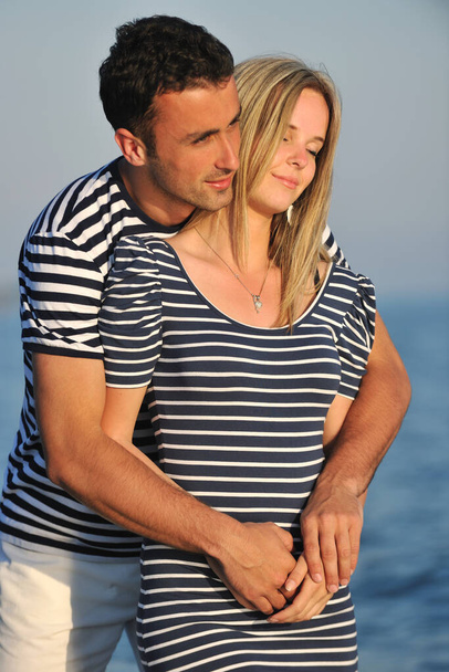幸せな若いカップルは日没時にビーチでロマンチックな時間を過ごす - 写真・画像
