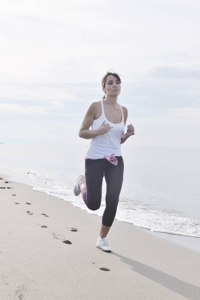 young healthy woman jogging and running at beach at early morning  - Foto, afbeelding
