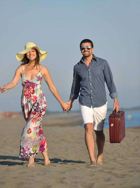 paar op het strand met reistas vertegenwoordigen vrijheid en grappige huwelijksreis concept - Foto, afbeelding