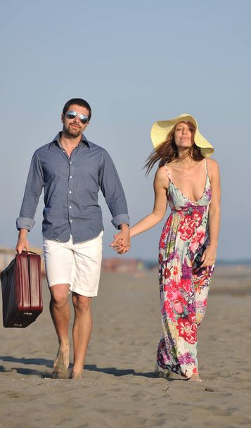 couple on beach with travel bag representing freedom and funy honeymoon concept - Foto, afbeelding