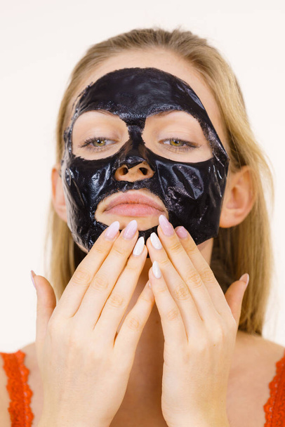 Girl with dried peel-off black mask on face - Foto, Imagen