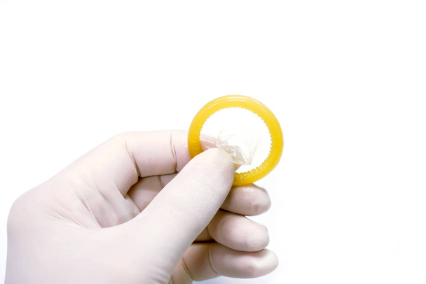 Docteur main dans le gant de latex médical ramasser un préservatif sur fond blanc
. - Photo, image