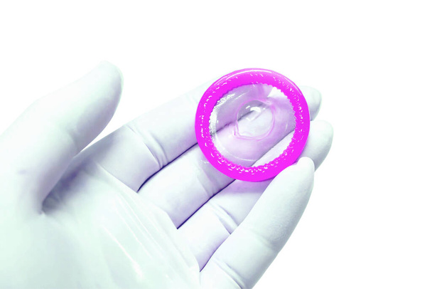 Bright violet condom on doctor hand in blue medical latex glove on white background. - Foto, Imagem