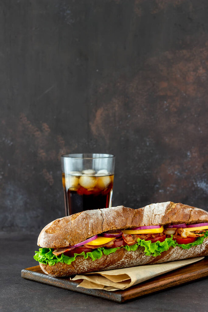 A sandwich of dark bread with salad, bacon, tomatoes, cheese and onions. Breakfast. Fast food. - 写真・画像