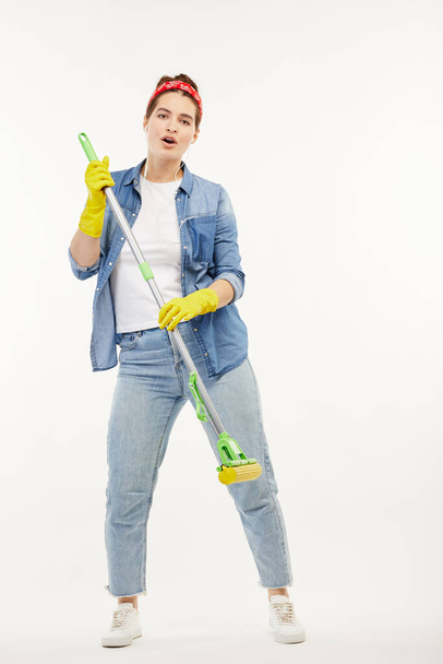 Pretty woman in work-wear holds a green mop and dances. - Foto, Imagen