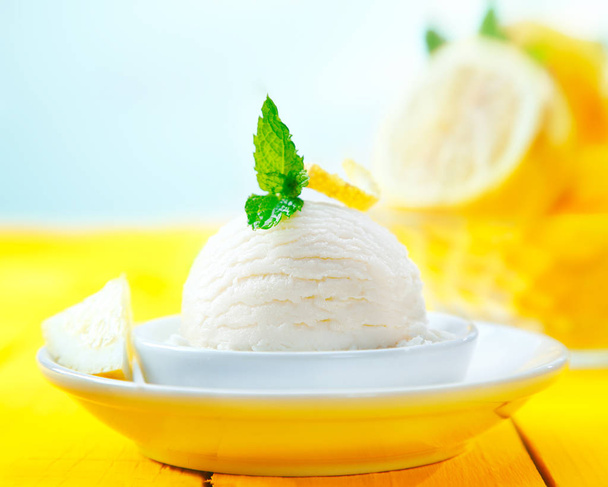 Scoop of tangy refreshing lemon sorbet icecream served for dessert on a yellow wooden table - Foto, immagini