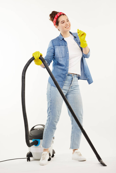 Pretty woman in work-wear uses a big wacuum cleaner and dances. - Foto, Imagem