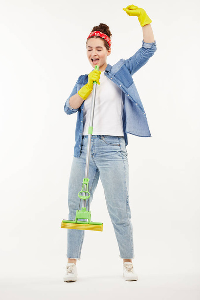 Pretty woman in work-wear holds a green mop and dances. - Foto, Imagen