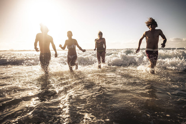 Junge Freunde laufen gemeinsam im Meerwasser und haben Spaß an einem sonnigen Sommerferientag  - Foto, Bild