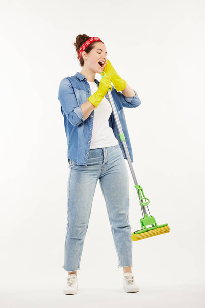 Pretty woman in work-wear holds a green mop and sings. - Fotoğraf, Görsel