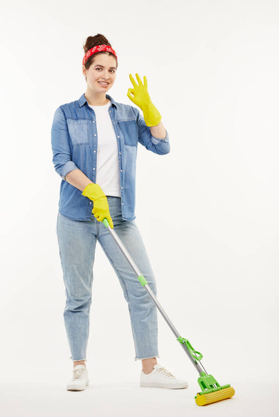 Pretty woman in work-wear holds a green mop. - Foto, Bild