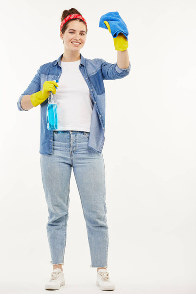 Pretty woman in work-wear shows how to clean windows. - Foto, Imagen