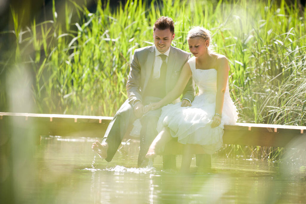 bride and groom sitting romantically on a lake - Photo, image