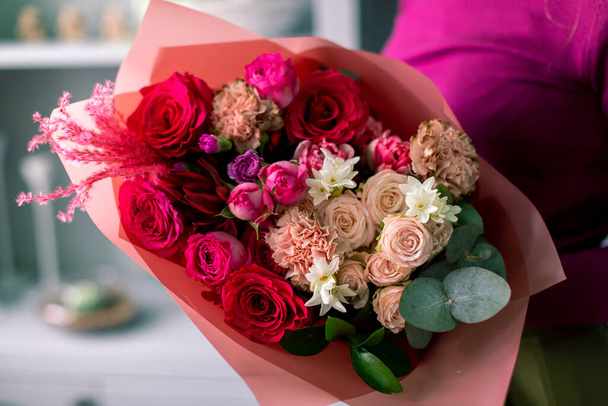 Close-up flowers in hand. Florist workplace. Woman arranging a bouquet with roses, chrysanthemum, carnation and other flowers. A teacher of floristry in master classes or courses - Foto, immagini