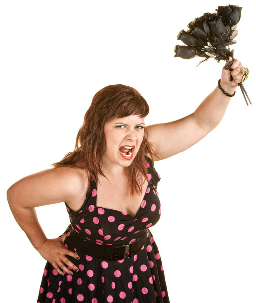Angry woman in pink polka dot dress holding black roses - Zdjęcie, obraz