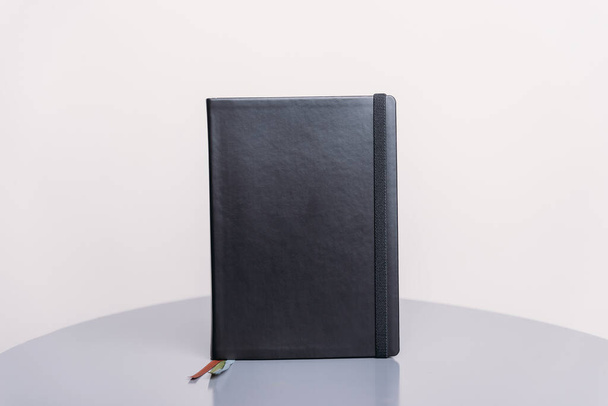 Livre noir, agenda ou planificateur debout sur une surface grise et fond blanc. Modèle de livre
. - Photo, image