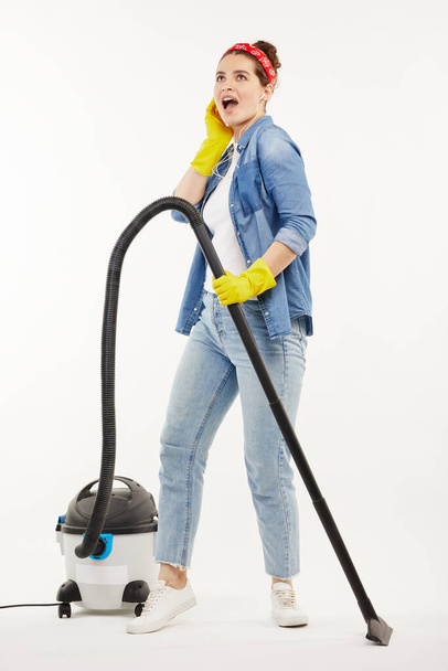 Pretty woman in work-wear uses a big wacuum cleaner. - Foto, imagen