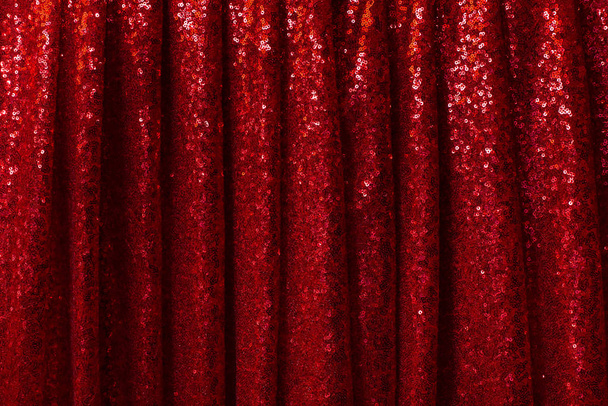 roter Vorhang aus glänzendem Stoff mit runden Falten, die in Falten hängen - Foto, Bild