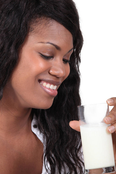 Afro-Amerikaanse vrouw glimlachend met glas melk - Foto, afbeelding
