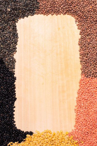 border of yellow,red,brown and black lentils on a board - Zdjęcie, obraz